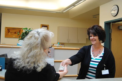 Picture of a female smiling and handing a female Admission Clerk money